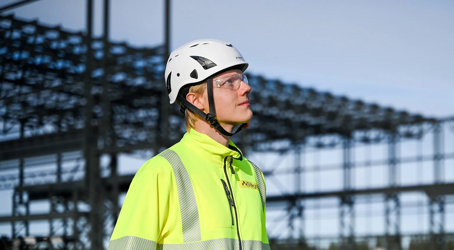 A man in a hard hat and high-visibility jacket working on site