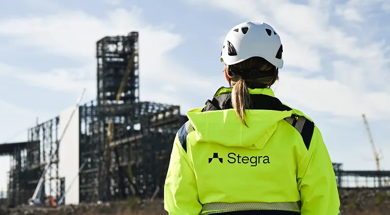A woman in high-vis and hard hat looking at a steel frame