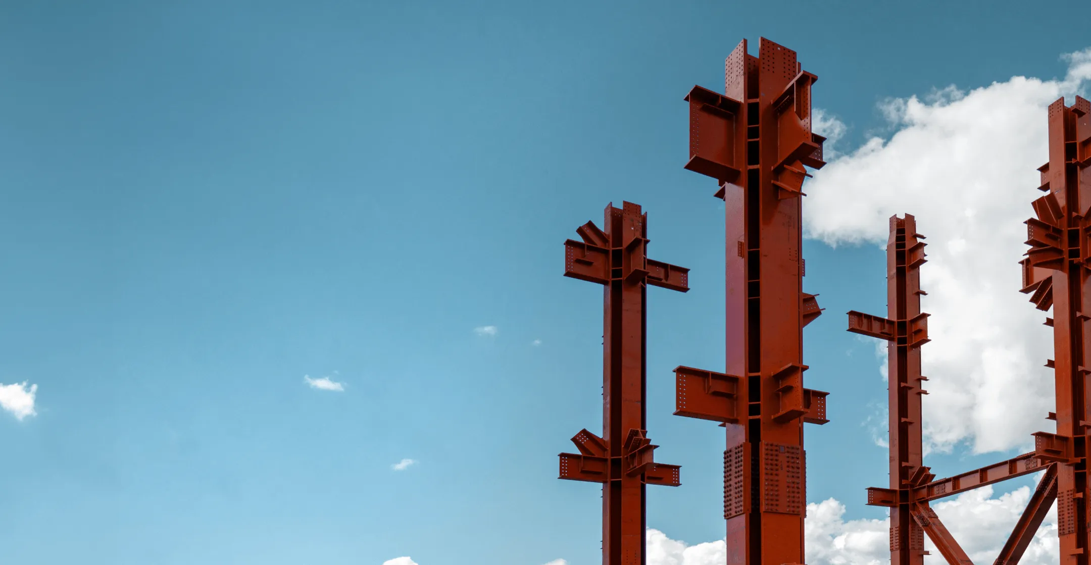 Four red steel pillars surrounded by blue skies and thin cloud