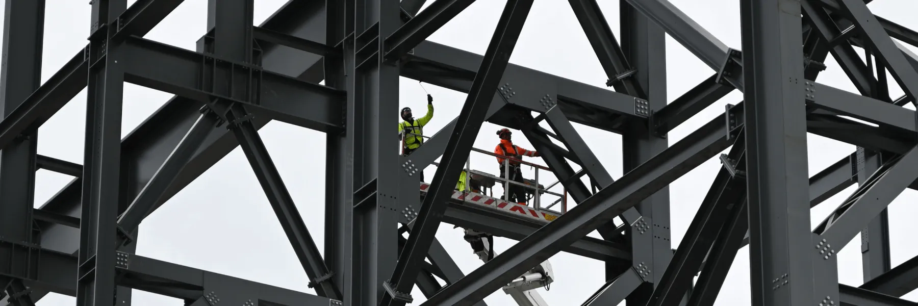 Employees work on-site high up among steel beams