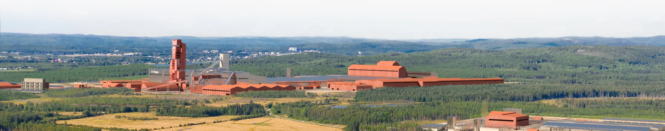 Large red steel plant surrounded by green fields