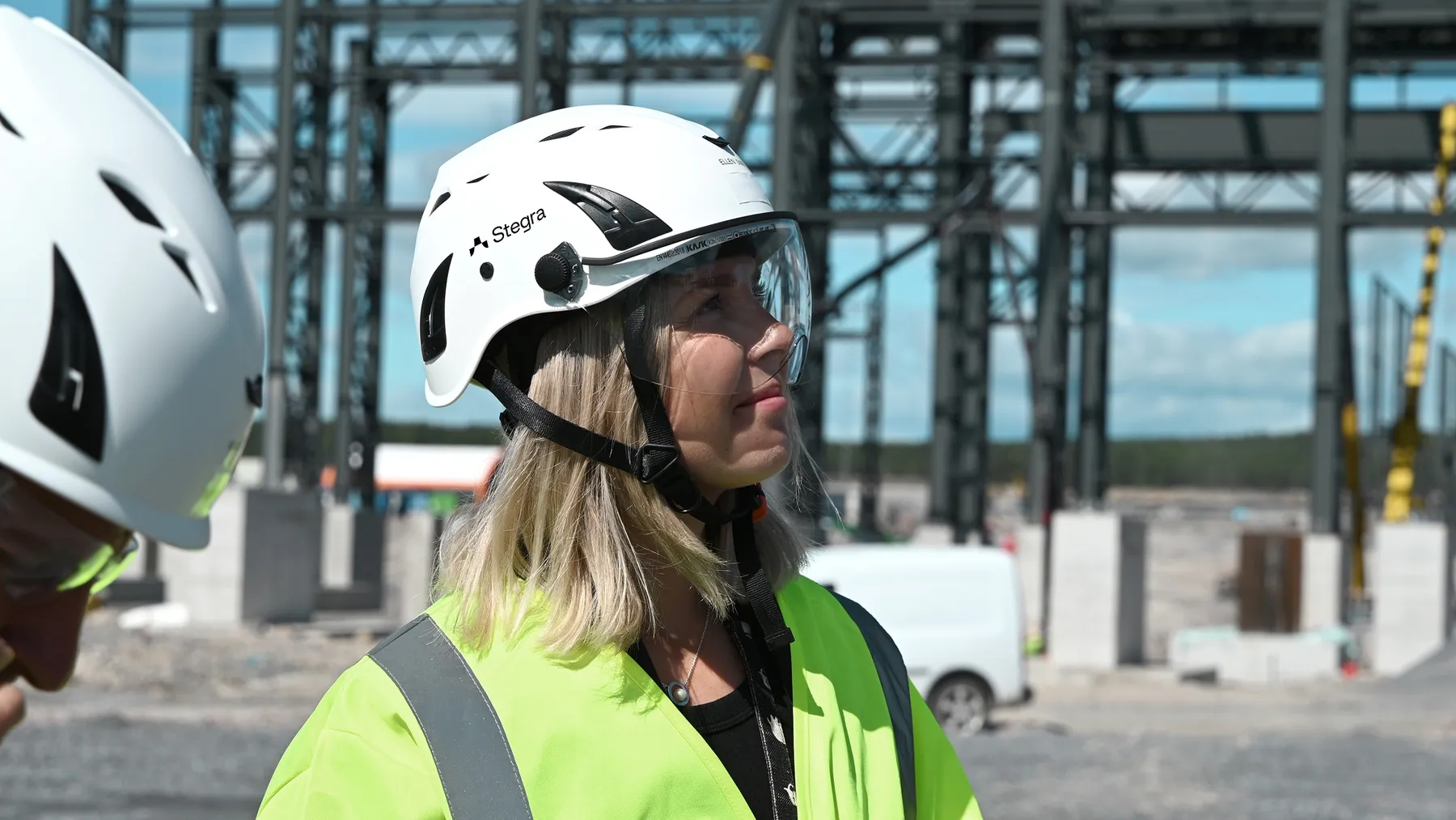 A blonde woman in a hard hat and high-visibility jacket